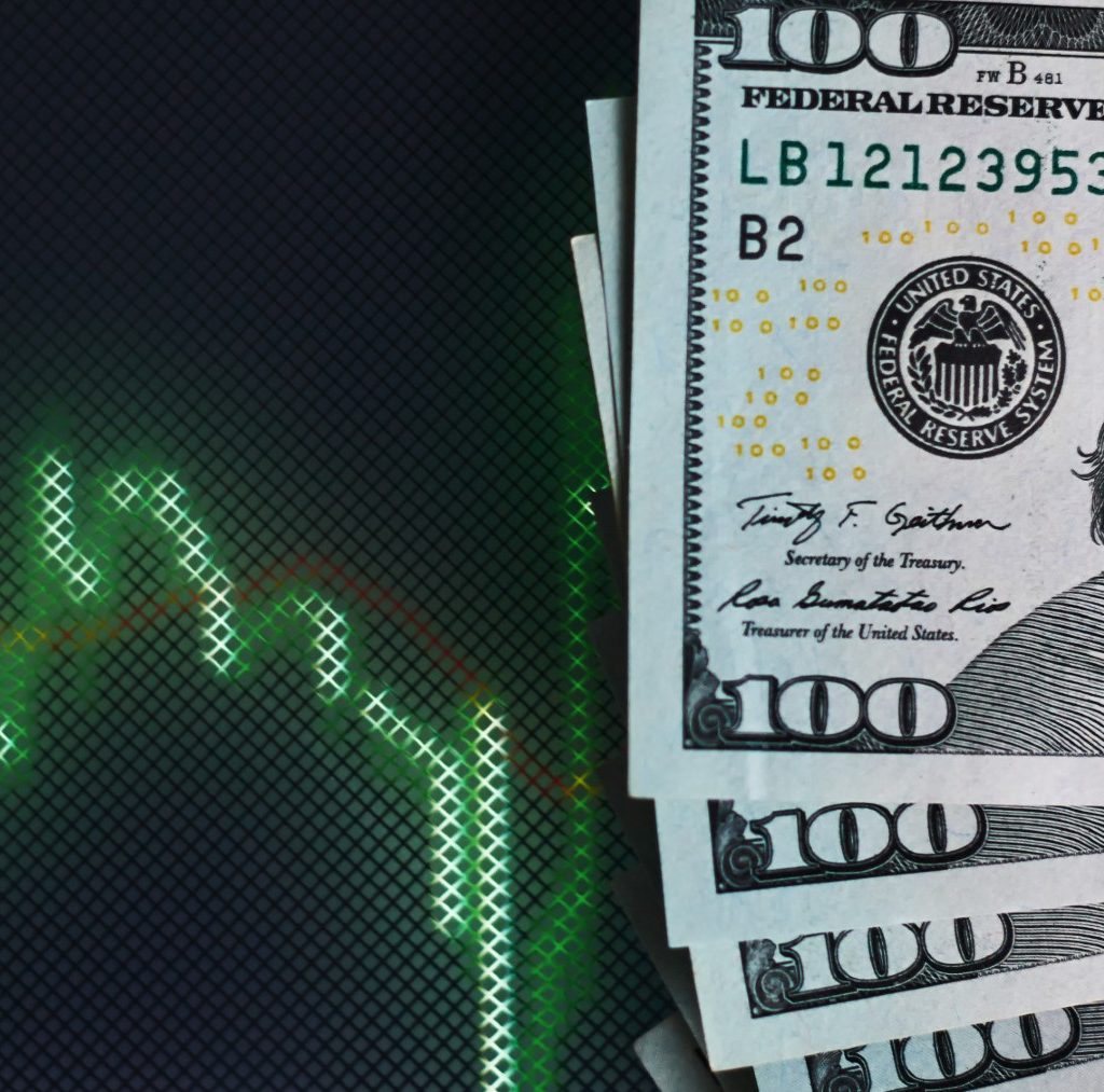 Billetes de cien dólares apilados sobre un fondo oscuro con un gráfico financiero verde en caída, simbolizando el nuevo carry trade argentino tras la eliminación del cepo cambiario.